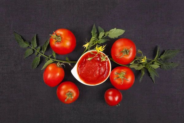 Verse tomaten op zwarte achtergrond met ketchup. — Stockfoto