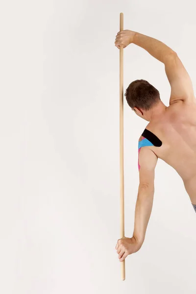 Man stretching with wooden pole — Stock Photo, Image