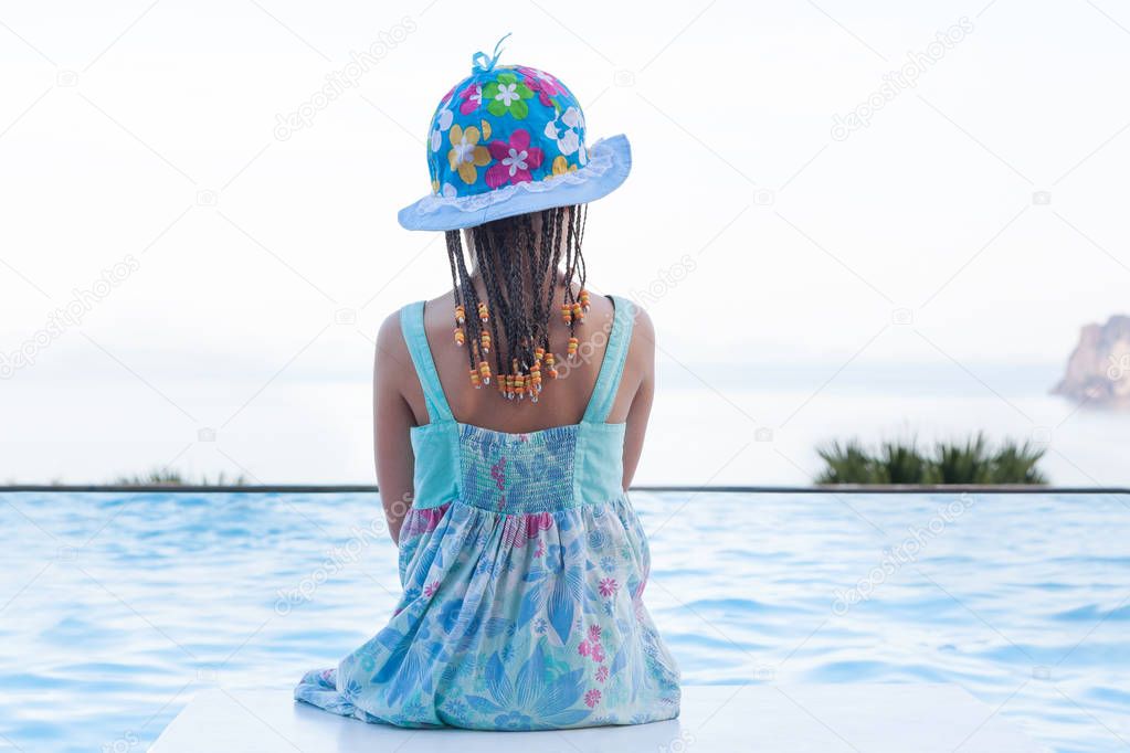 Cute girl overlooking ocean from infinity pool.