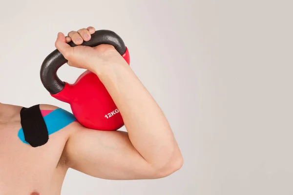 Homem musculoso segurando kettlebell na mão . — Fotografia de Stock