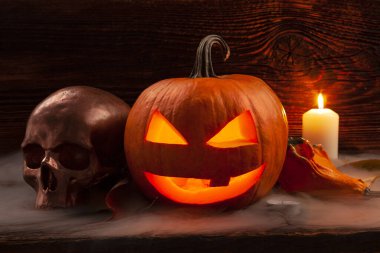 Cadılar Bayramı geçmişi. Korkunç balkabağı ve korkunç kafatası ahşap arka planda.