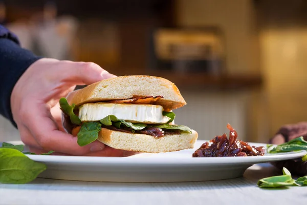 Sanduíche Ciabatta Com Queijo Cabra Fresco Bacon Espinafre Mão Masculina — Fotografia de Stock