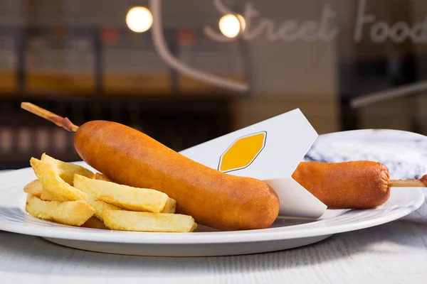 Traditional American street food corn dogs with french fries on white plate. Take away, street food.