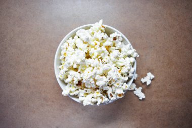 Tahta arka planda patlamış mısırlı kase, seçici odak.