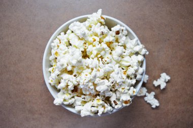 Tahta arka planda beyaz kasede patlamış mısır, seçici odak.