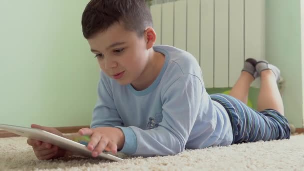 Мальчик в комнате играет на планшете — стоковое видео