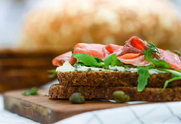 Smoked salmon sandwich with cheese, pistachio and salad leaves,