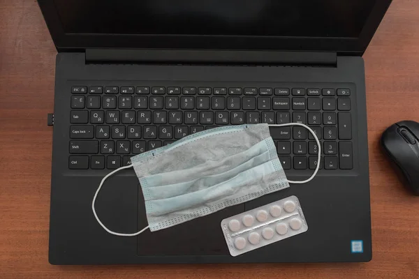 Tıbbi maske ve tabletler laptopta.