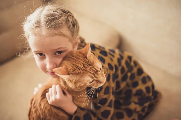 Kız ve kırmızı kedi evde oynuyorlar.