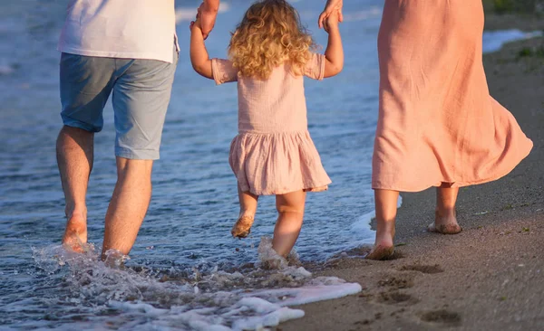Mom dad and daughter walking on the beach
