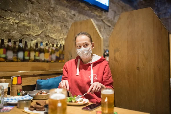 Girl sitting in a bar in a medical mask