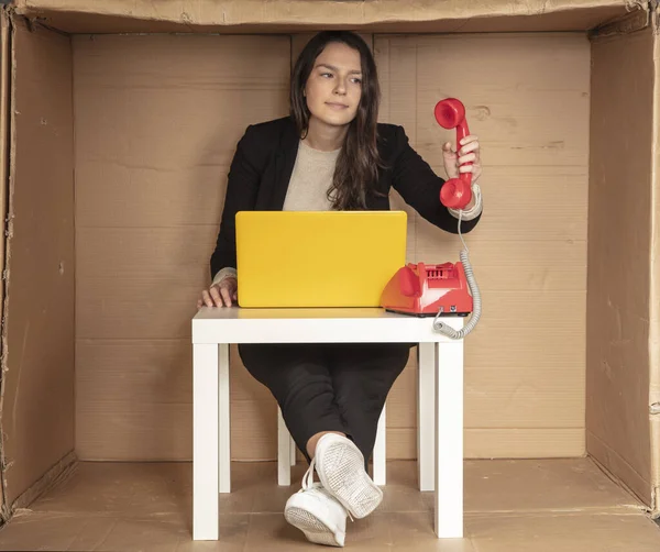 beautiful businesswoman sits in a cramped paper office, picks up the phone