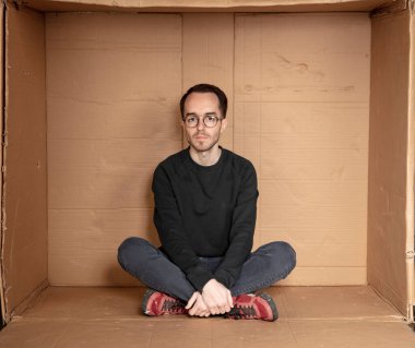 Küçük, sıkışık bir ofiste çalışan genç bir adam çalışmaya hazırlanıyor.