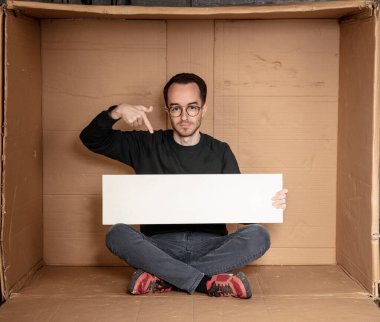 Genç işsiz bir adamın elinde beyaz bir pano, reklam için bir yer, yardım çığlığı fikri