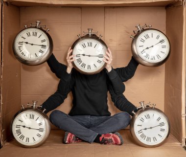 Genç işsiz bir öğrenci sıkı bir karton kutunun içinde oturuyor, deneyimsiz işsizlik fikri, zamanın geçişini simgeleyen bir saatin elindeki saat.