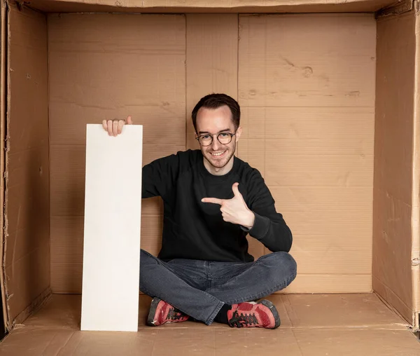 Genç işsiz bir adamın elinde beyaz bir pano, reklam için bir yer, yardım çığlığı fikri