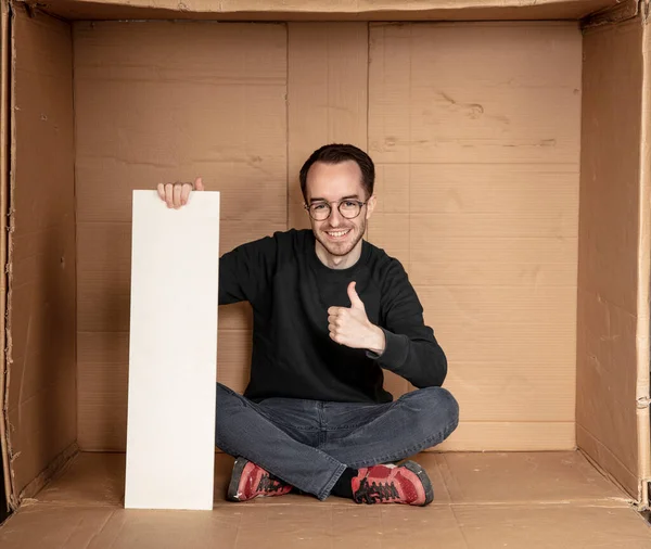 Genç işsiz bir adamın elinde beyaz bir pano, reklam için bir yer, yardım çığlığı fikri