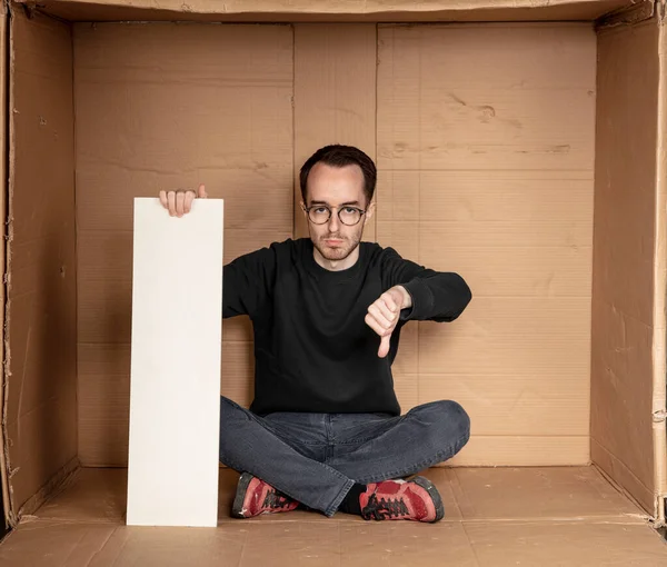 Genç işsiz bir adamın elinde beyaz bir pano, reklam için bir yer, yardım çığlığı fikri