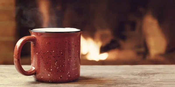 Roter Becher mit heißem Tee vor dem brennenden Kamin, Gemütlichkeit, Winterurlaub und Wärme am Herd — Stockfoto