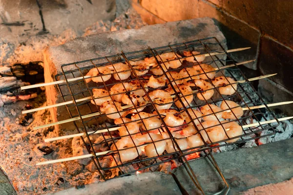 Shrimp frying on bamboo skewers on hot coals in a fireplace — Stock Photo, Image