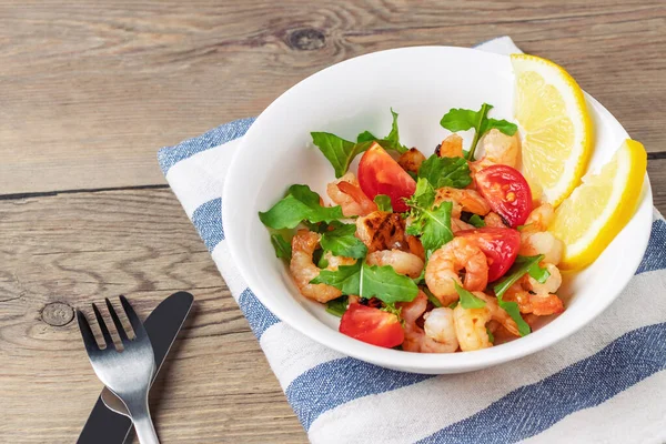 Fresh homemade salad of shrimp, arugula and tomato in a white plate on a wooden table — Stock Photo, Image