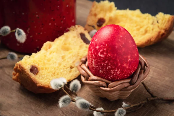 Красное пасхальное яйцо, кусочек пасхального торта и чашка кофе на разделочной доске на темном столе - традиционный пасхальный завтрак — стоковое фото