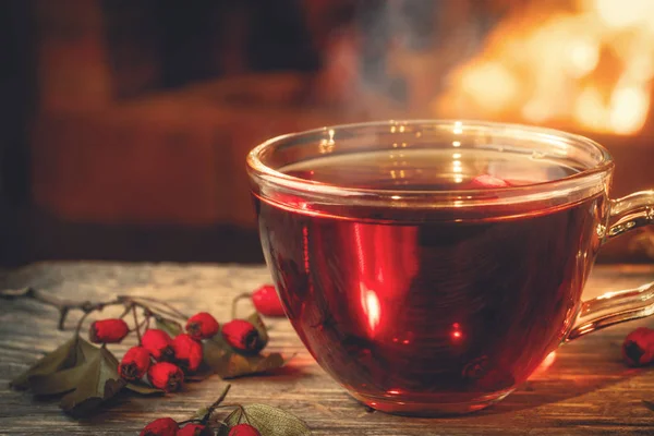 Tee mit Weißdorn in einer Glasschale auf einem Holztisch in einem Raum mit brennendem Kamin — Stockfoto