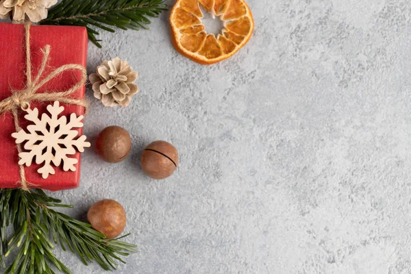 Fondo gris de Navidad o Año Nuevo con decoraciones de materiales naturales: ramitas de árboles de Navidad, nueces, conos, copo de nieve de madera y naranja seca Imagen De Stock