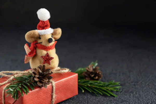 Little toy Christmas mouse, gift and decorations on a black table. Christmas composition with the symbol of 2020 according to the Chinese horoscope