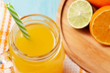 Mason kavanozunda taze sıkılmış portakal suyu, portakallar ve ahşap kapta limon.