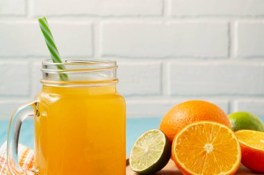 Ev yapımı taze sıkılmış portakal suyu mason kavanozunda, portakallar ve kireç ahşap kapta, kopyalama alanı.