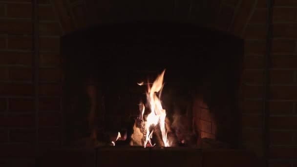 Llama ardiente en una chimenea de ladrillo rojo en una casa de campo por la noche — Vídeo de stock