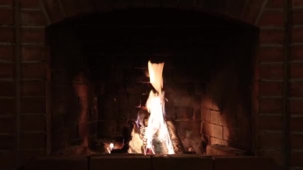 Llama ardiente en una chimenea de ladrillo rojo en una casa de campo por la noche — Vídeos de Stock