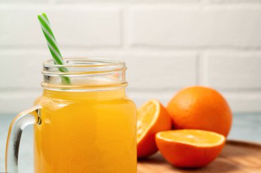 Ev yapımı taze sıkılmış portakal suyu mason kavanozunda, portakallar ahşap kapta yakın plan, kopyalama alanı.