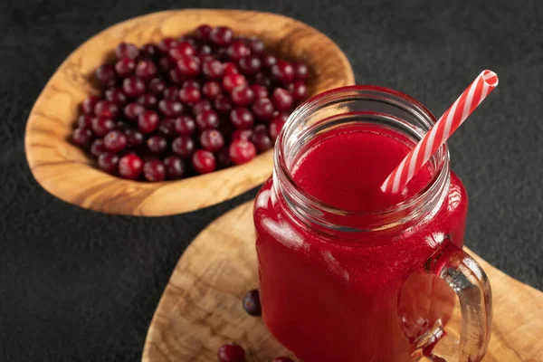 Healing cranberry juice in a glass jar-mug with a straw on black table. Healthy eating concept — Stock Photo, Image