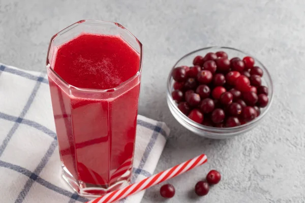 Een glas met zelfgemaakt vers cranberrysap en een kom cranberry 's op een grijze betonnen tafel — Stockfoto