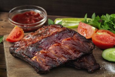 Ketçap ve sebzeli ahşap kesim tahtasında ızgara domuz kaburgası.