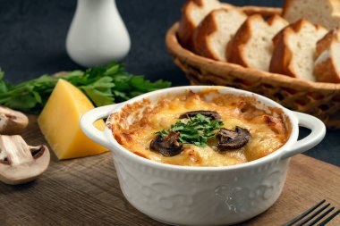 Tavuklu, mantarlı ve peynirli güveç. Rusya 'da jülyen olarak biliniyor. Tahtada otlar var.