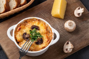 Tavuklu, mantarlı ve peynirli güveç. Rusya 'da ahşap bir tahtanın üzerinde otlarla dolu beyaz kâse içinde julienne olarak bilinir.