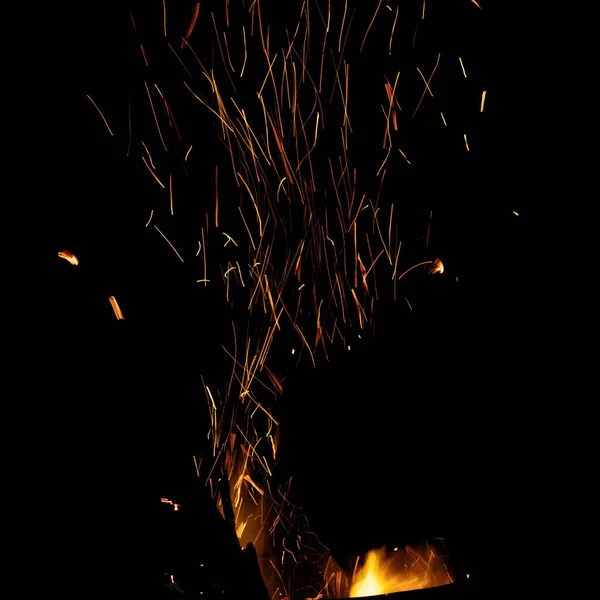 Flamme de feu de joie avec des étincelles lumineuses. Isolé sur fond noir — Photo