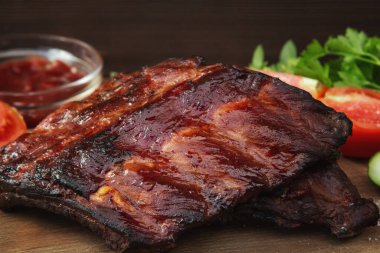 Ketçap ve sebzeli ahşap kesim tahtasında ızgara domuz kaburgası.