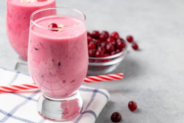 Gri bir masada iki bardak taze yoğurt, yulaf ezmesi ve kızılcık. Sağlıklı yeme kavramı