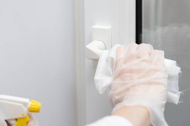 Coronavirus KOVID-19 'un yayılmasını önlemek için yapılan eylemler, kapı kolunun dezenfekte edilmesi. Eldivenler, kapı kolunu dezenfektanla siler.