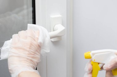 Coronavirus KOVID-19 'un yayılmasını önlemek için yapılan eylemler, kapı kolunun dezenfekte edilmesi. Eldivenler, kapı kolunu dezenfektanla siler.