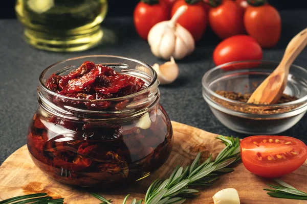 Cozinhar tomates secos ao sol em um frasco de vidro com azeite, alho e alecrim — Fotografia de Stock