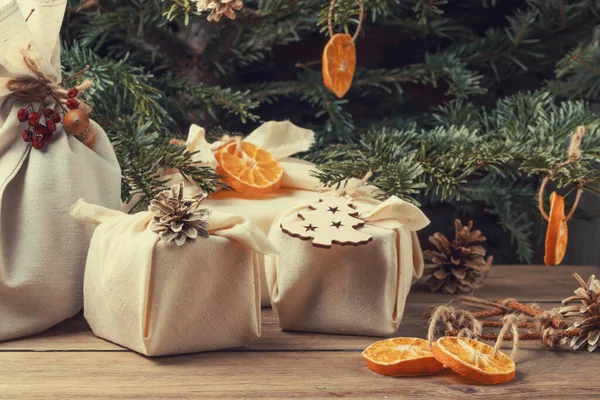 Concept de Noël zéro déchet. Emballé dans des cadeaux en tissu naturel et des décorations à partir de matériaux naturels sur une table en bois — Photo