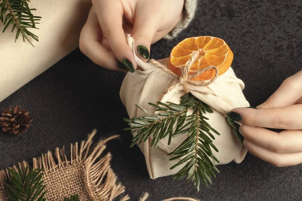 Отходы и экологически чистые технологии. Женские руки обернуть подарки в натуральную ткань с орнаментами из натуральных материалов — стоковое фото