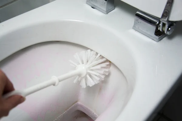 Een vrouw reinigt een badkamer toilet met een scrub borstel — Stockfoto