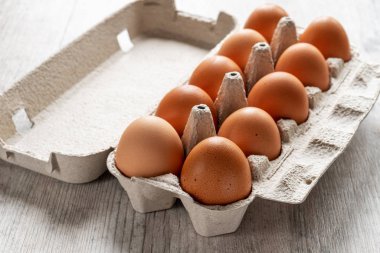 Ahşap arka planda karton kutuda çiğ tavuk yumurtası.