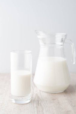 Beyaz bir arka planda, tahta bir masada bir bardak süt.